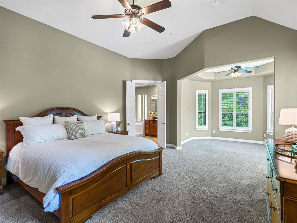 The spacious primary retreat is a true sanctuary, offering comfort, style, and privacy. Two bright windows with plantation shutters bring in soft natural light, while 5-inch baseboards and thoughtful touches—like a wall switch wired to control bedside lamps—add convenience and charm.