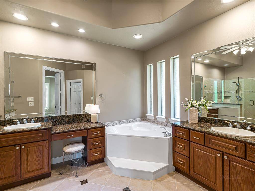 Completing this luxurious retreat is a private ensuite bathroom, designed as a serene escape for rest and rejuvenation. The space features elegant tile flooring with granite inlays and granite countertops with an overmount sink, combining beauty and functionality.