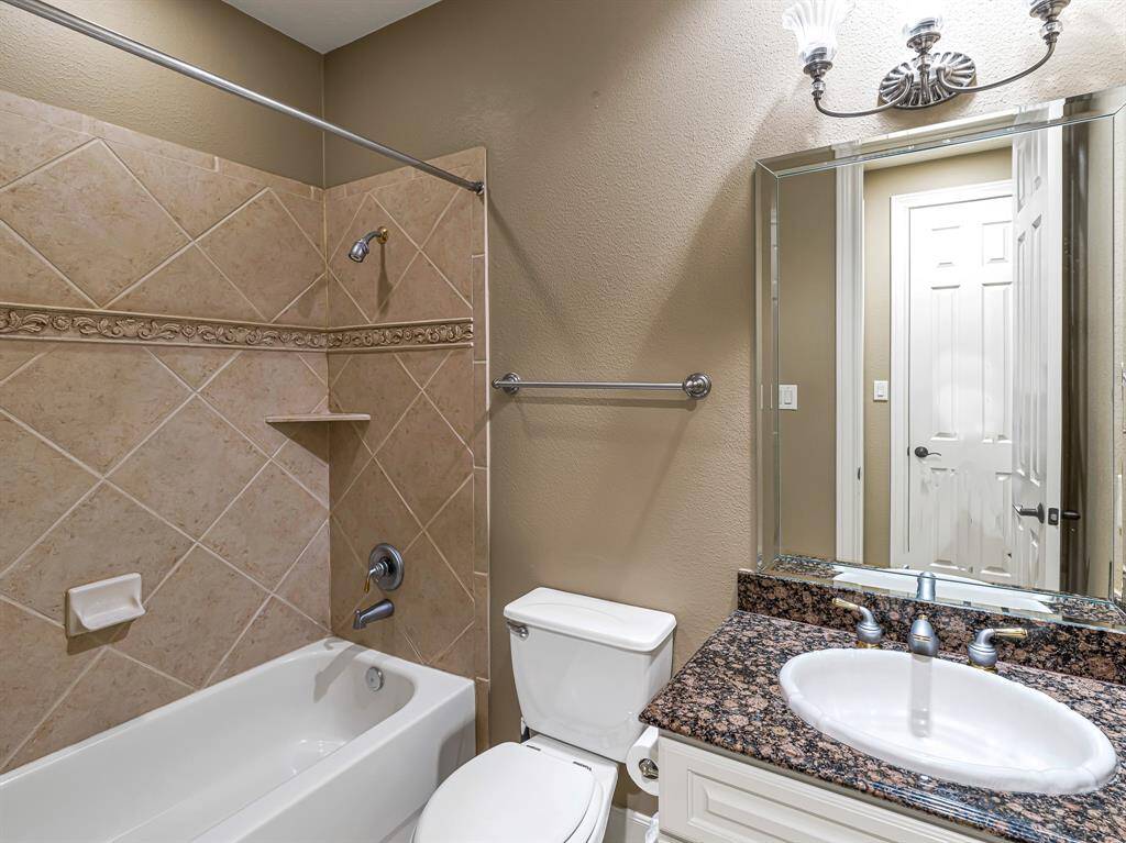 The third full bathroom offers a granite-topped vanity with overhead lighting and a tub/shower combo, combining style and functionality.