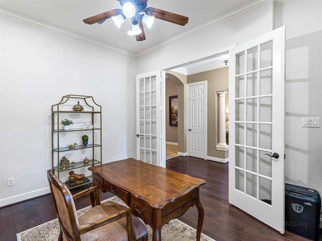 This thoughtfully designed home office features engineered wood flooring for a sleek, polished look, complemented by a ceiling fan & crown molding that add an extra layer of sophistication. 5-inch baseboards provide a refined finishing touch, elevating the room’s overall aesthetic.