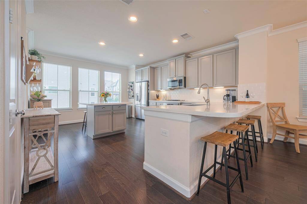 Large kitchen with white countertops with breakfast bar seating