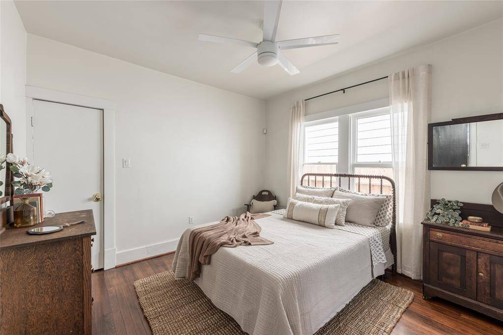 The sunlit primary bedroom offers a peaceful escape with vintage-inspired details and warm wood floors, blending character with calm.