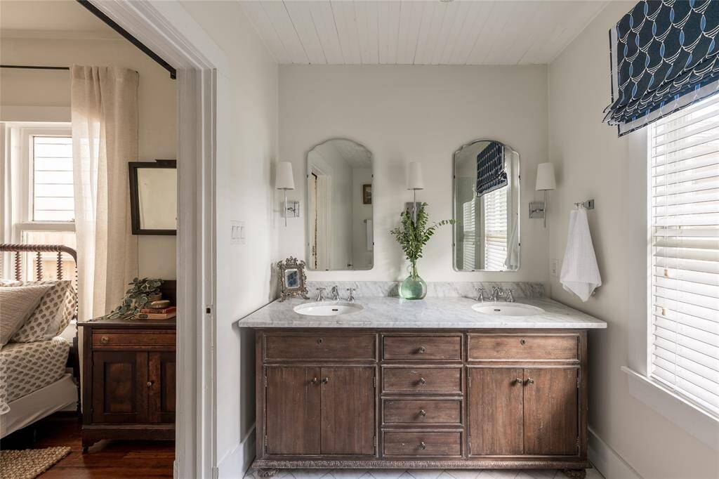 Dual sinks rest atop a rich wood vanity, offering both function and beauty in a bathroom defined by warm tones and clean lines.