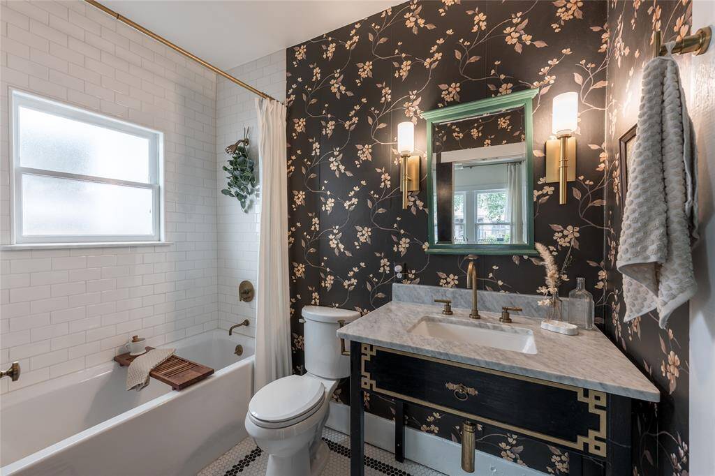 The guest bath features a soaking tub, polished tile, and brass fixtures making this space as functional as it is unforgettable.