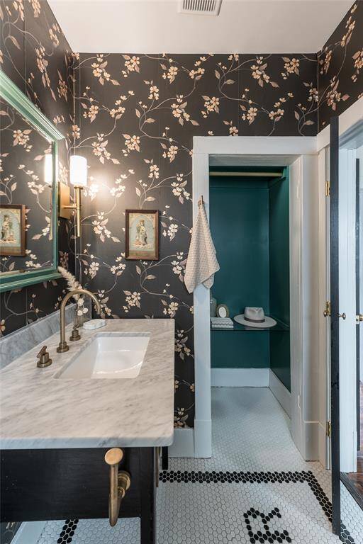 Wrapped in bold black floral wallpaper and finished with gold hardware, this guest bath feels like a boutique hotel experience.