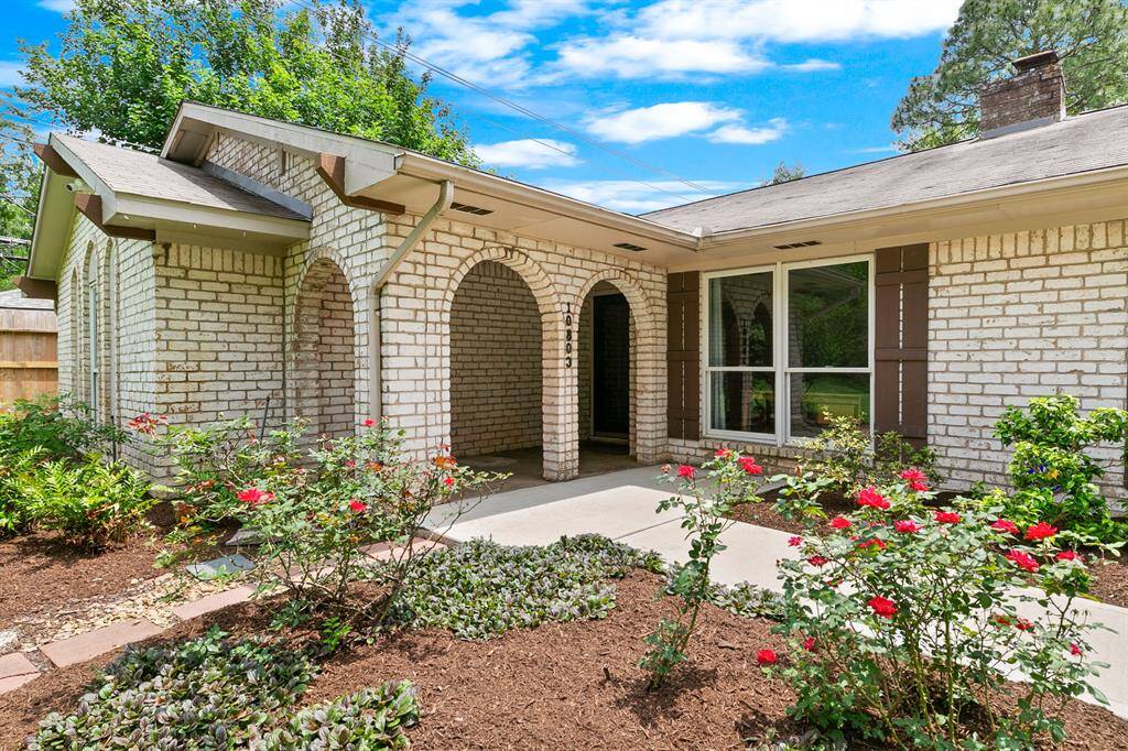 Charming brick home with archways and a welcoming front courtyard. Features large windows, landscaped garden, and a cozy porch area. Ideal for enjoying outdoor views and natural light.