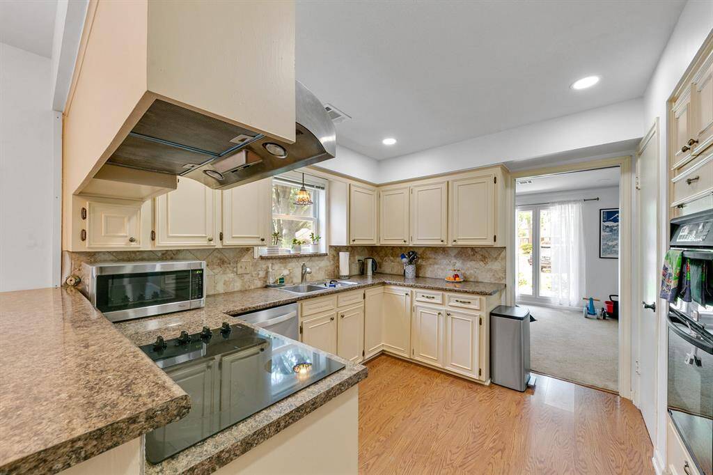 Spacious kitchen featuring off-white cabinetry, a double oven, an electric cooktop, and plenty of counter space.