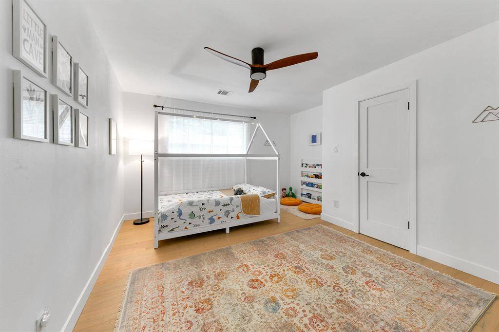 This bright, airy room features a light wood floor, white walls, and a ceiling fan.
