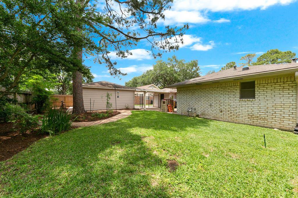 Spacious backyard with lush grass, mature trees, and a clear view of the home's exterior. Ideal for outdoor activities and relaxation.