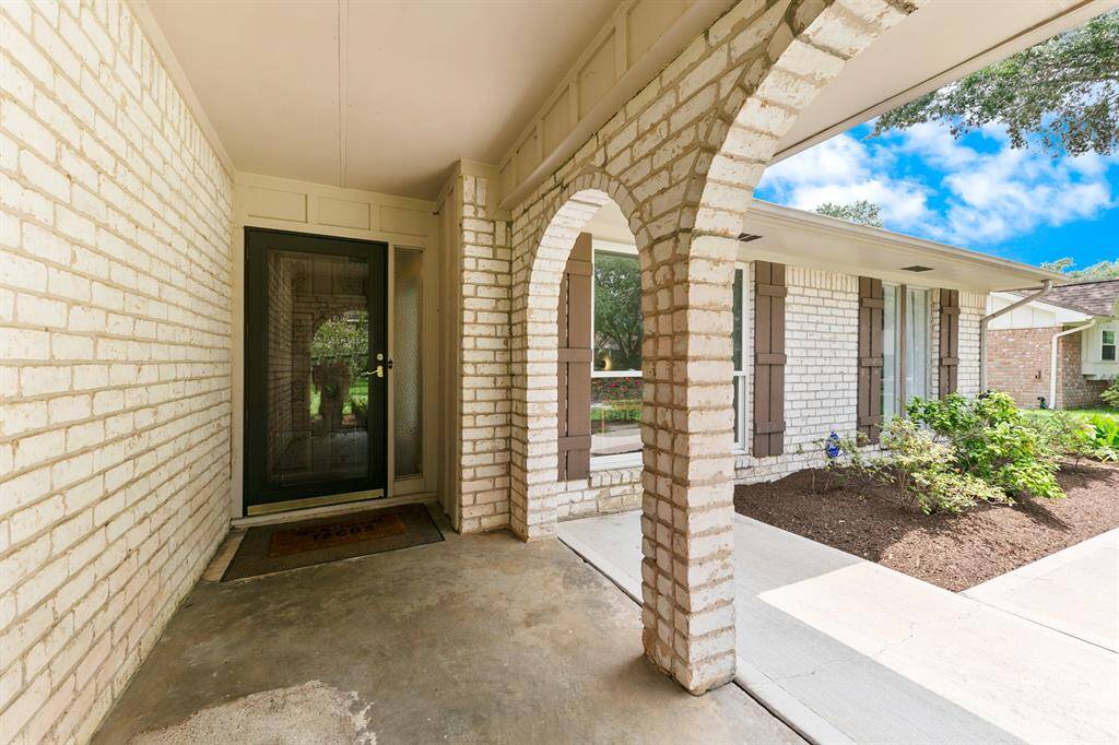 Charming front porch with arched brickwork and a glass door entry, offering a welcoming entrance.
