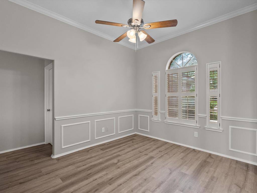 Bright dining room with elegant wainscoting, wood-look LVT flooring, and a ceiling fan.