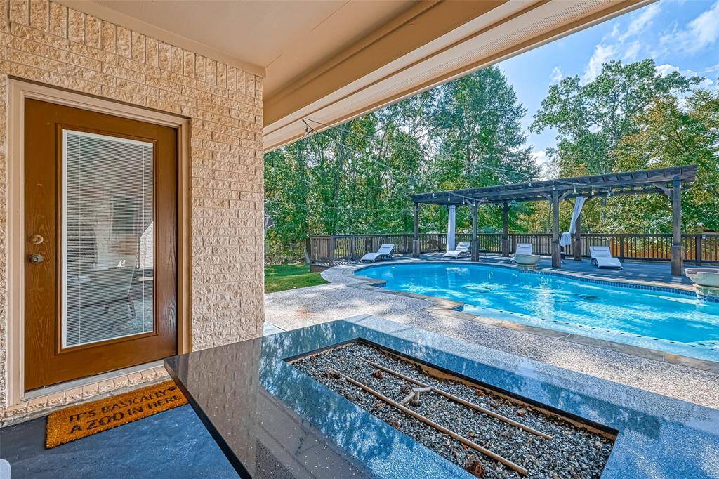 Poolside Views – Step outside to a sparkling pool surrounded by lush trees and a generous patio for entertaining.
