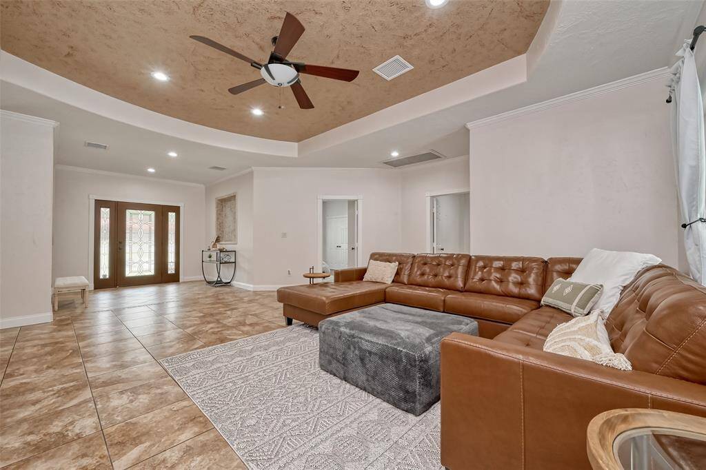 Spacious living room with a rich leather sectional and tray ceiling detail, perfect for relaxing or hosting guests in style.