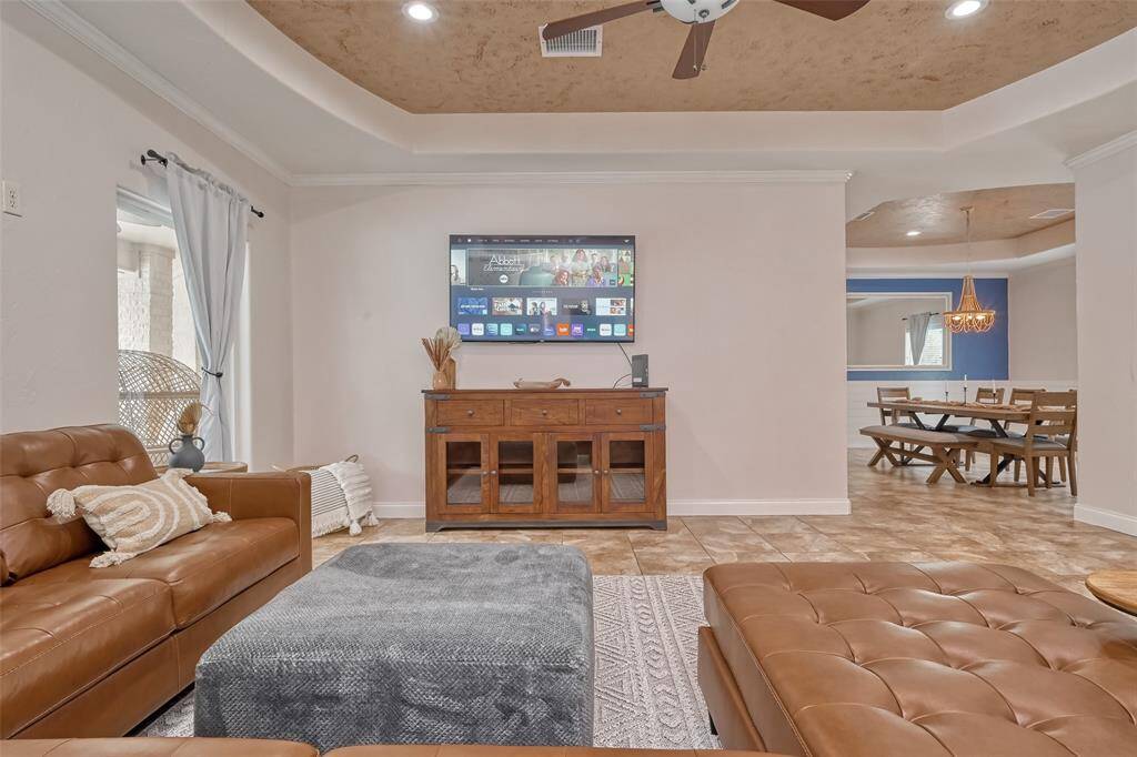 Living Room View Toward Dining – Spacious living area with a mounted smart TV, cozy leather sectional seating, and direct sightline into the elegant dining room, creating a seamless open-concept feel.