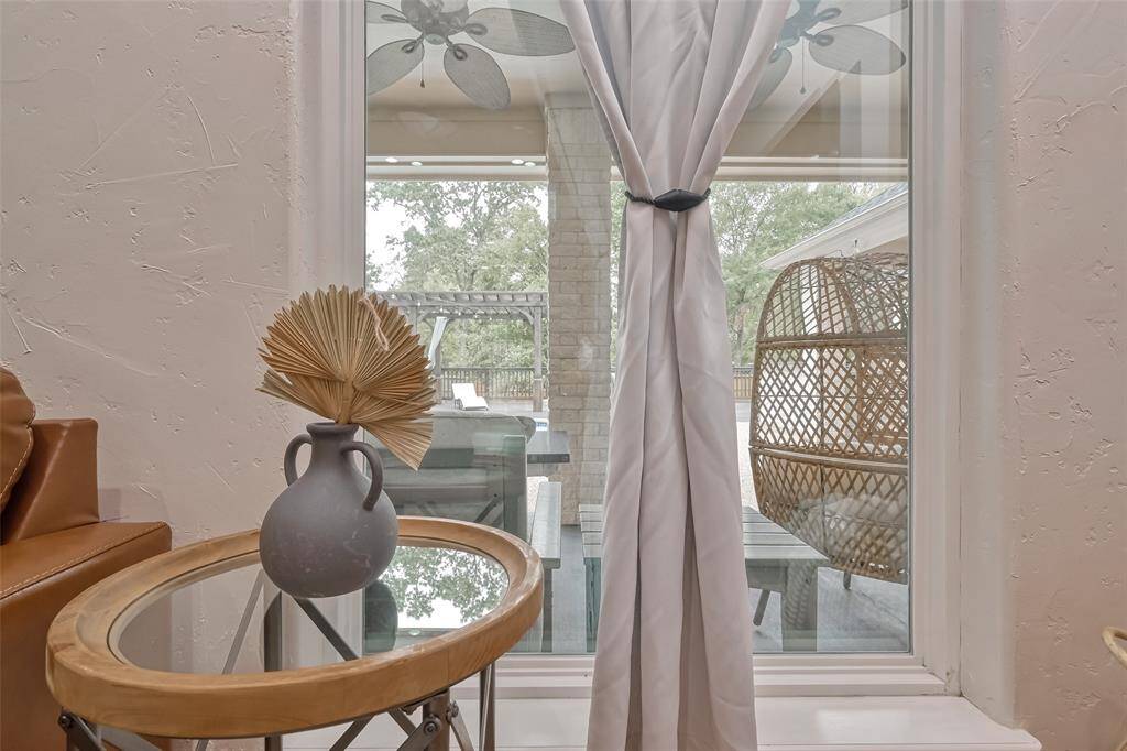 Window View to Backyard – Charming window-side nook with natural light and views of the covered patio and outdoor seating area, accented by soft curtains and a decorative vase.