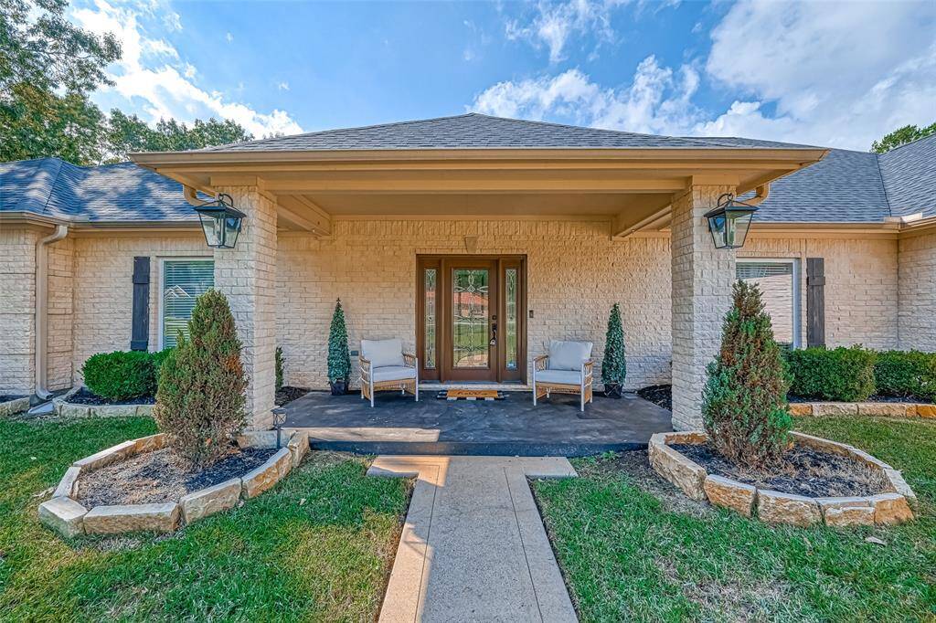 Charming covered front porch with cozy seating area and classic lantern lights invites you to relax and enjoy the serene surroundings.