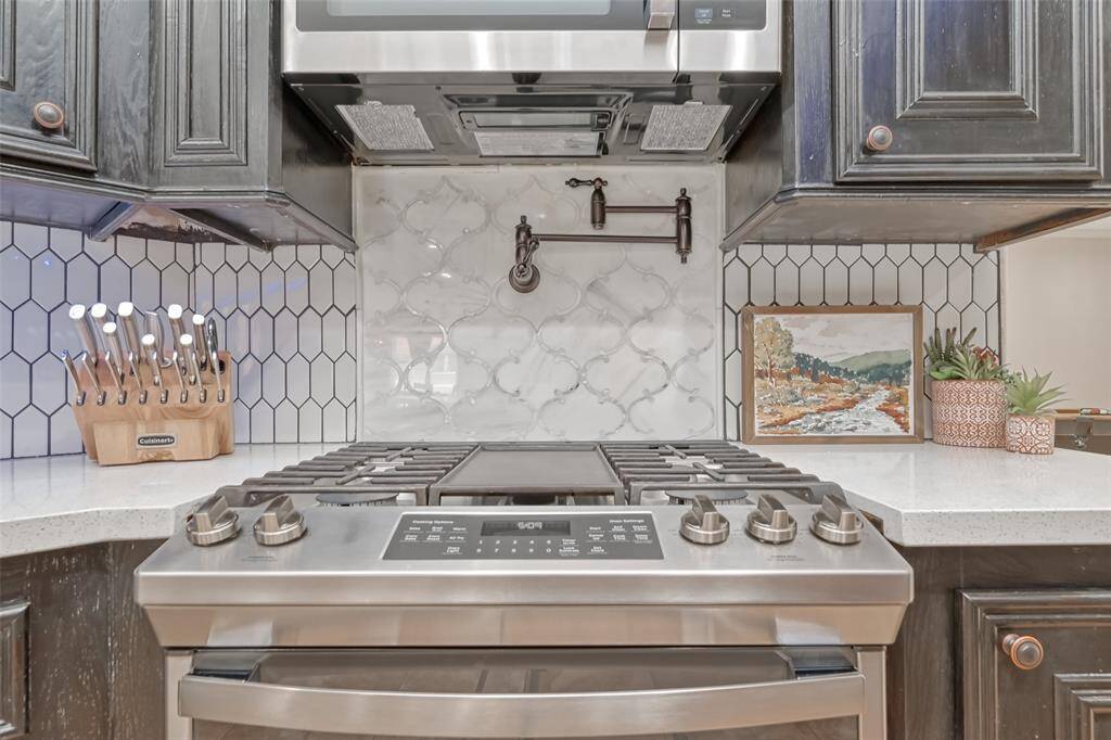 Kitchen Stove & Pot Filler – Up-close detail of the chef-grade gas stove with a stylish tile backsplash and convenient pot filler, framed by dark custom cabinetry.