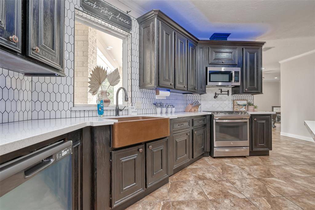 Sleek and stylish, this kitchen features custom cabinetry, a deep copper farmhouse sink, and modern appliances with elegant tile backsplash accents.