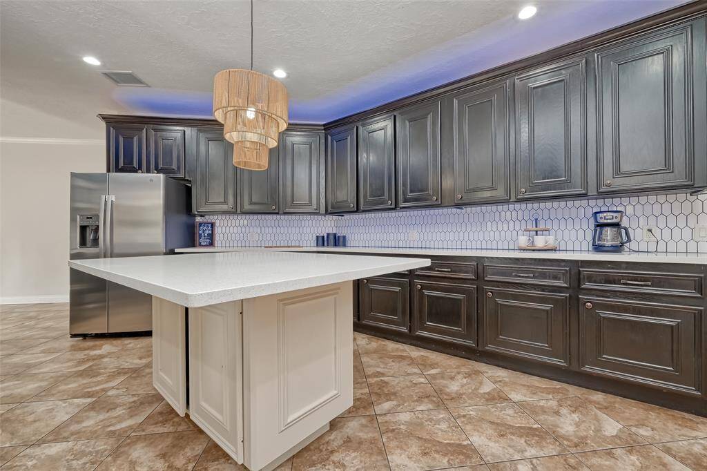Enjoy ample counter space and stunning dark cabinetry that contrasts beautifully with bright quartz countertops and a designer light fixture.