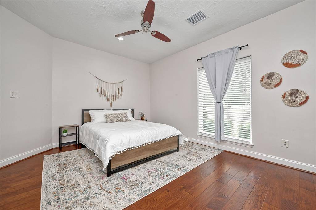 This guest bedroom offers warmth and simplicity with beautiful hardwood floors, natural light, and calming minimalist decor.
