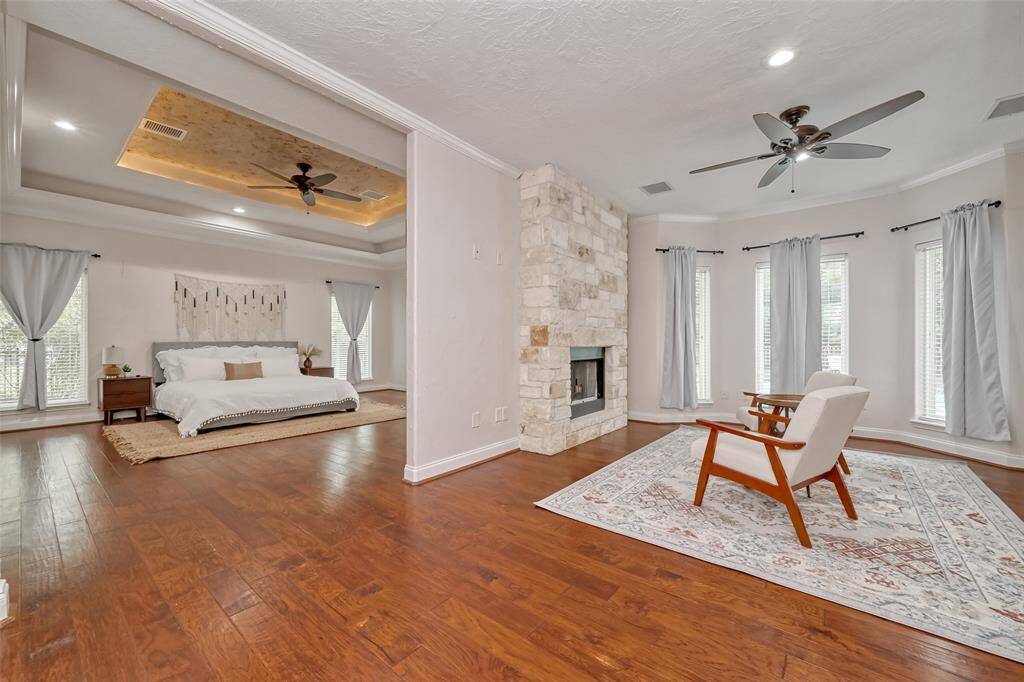 Retreat to your spacious primary suite with a cozy fireplace sitting area, rich wood floors, and walls of windows for peaceful views.