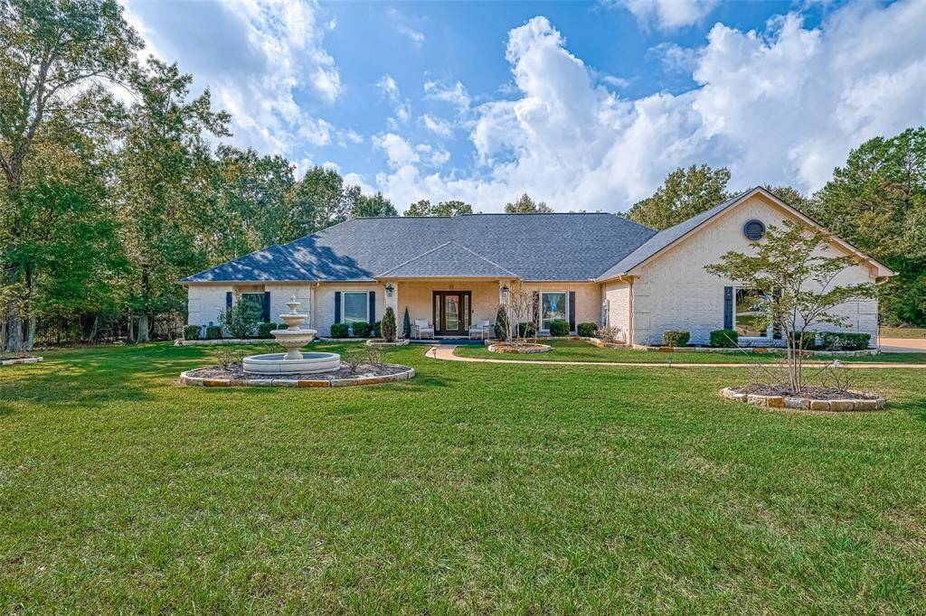 Grand curb appeal welcomes you with a manicured lawn, circular walkway, and elegant fountain—perfectly set on a spacious lot in a peaceful, wooded setting.