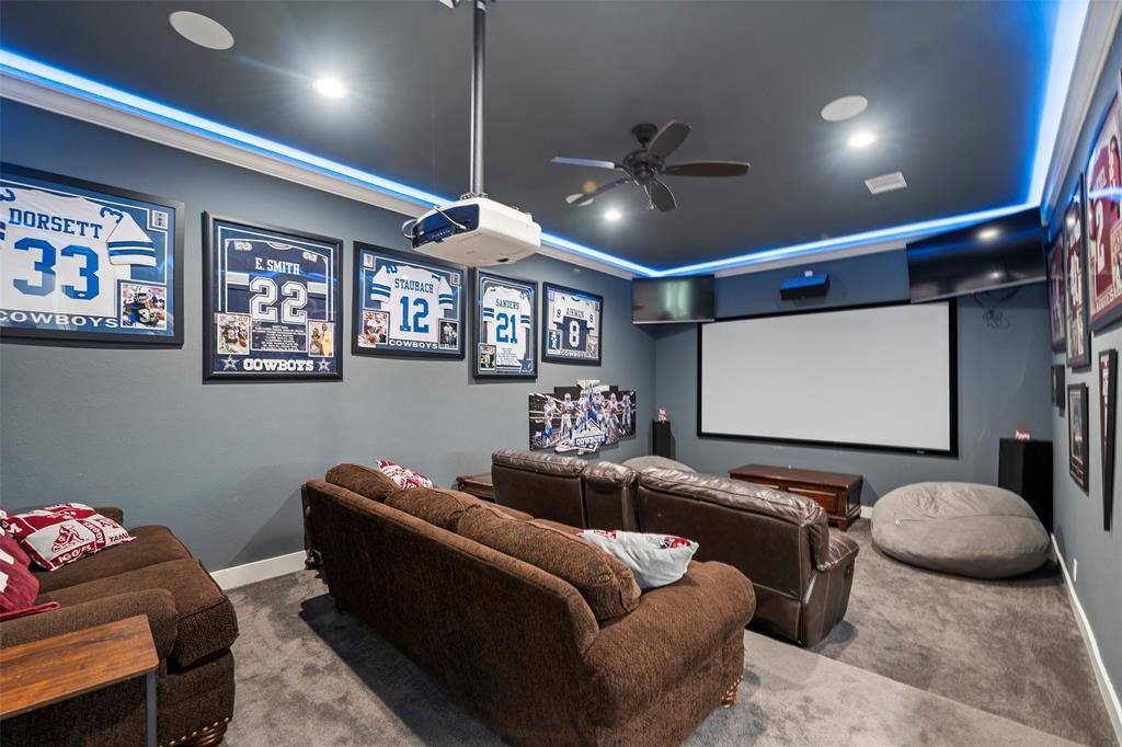Media room designed for entertainment with multi-level flooring, a wet bar, a beverage fridge, & crown molding w/rope lighting.