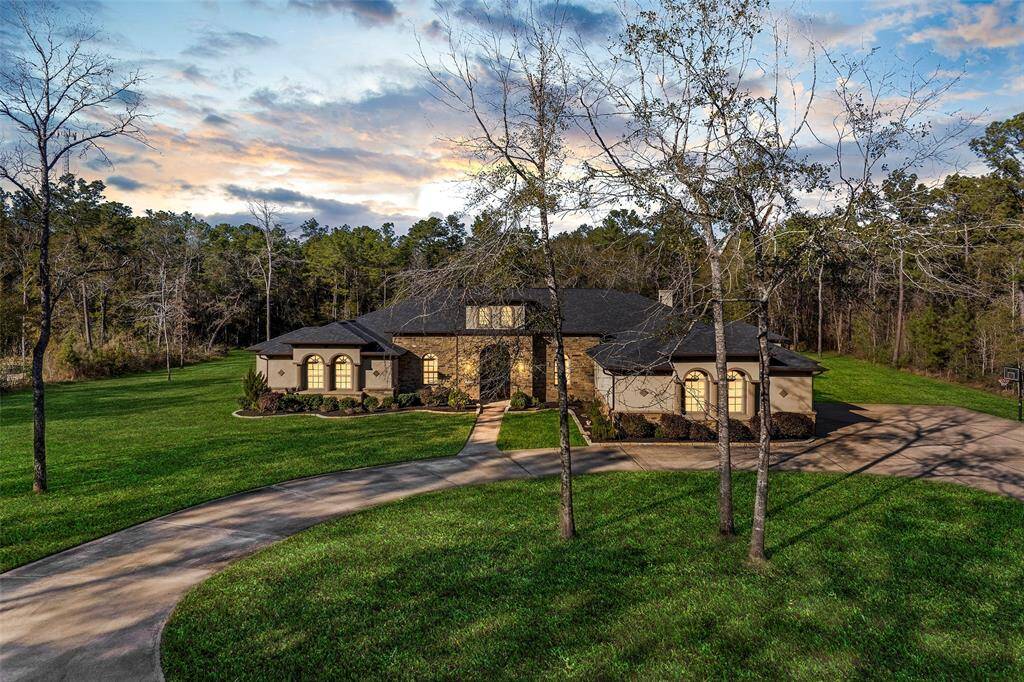 The open layout highlights a chef’s island kitchen with custom cabinets, a pot filler, under/above cabinet lighting, and a barn door pantry, overlooking a family room with a wood-burning fireplace, wooden beams, and large picture windows framing back acreage views. Enjoy a game room, media room with tiered flooring, wet bar, and crown molding with rope lighting.
