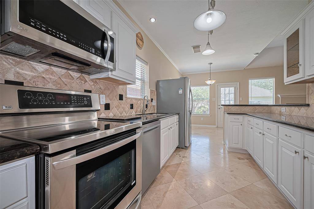 Kitchen offering an electric range, built in microwave, granite counters