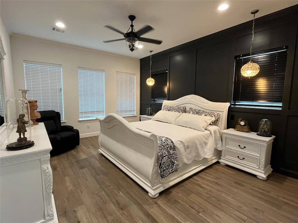 Primary bedroom with accent wall and upgraded lighting