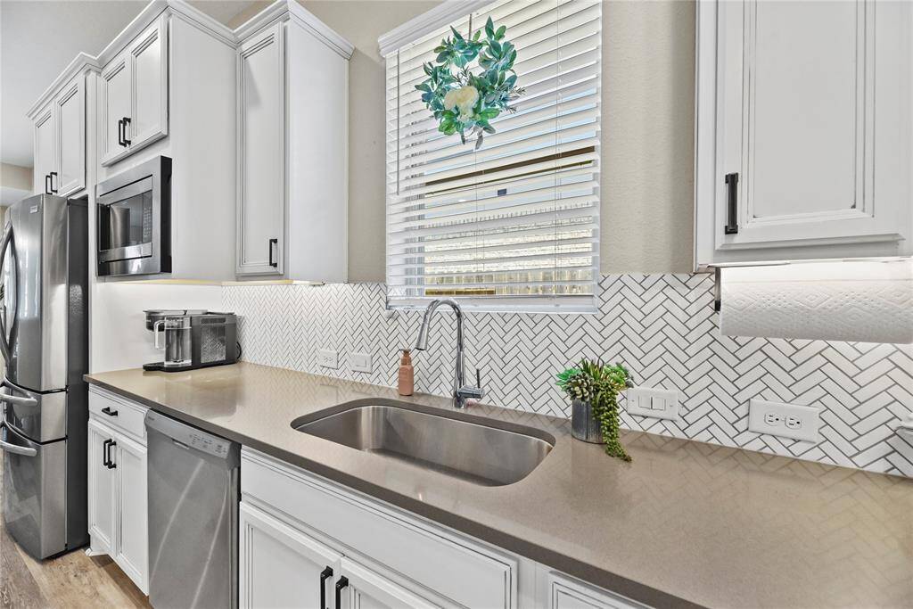 You will love the herringbone tile backsplash and also features a large window above the sink for natural light with ample prep countertop space.