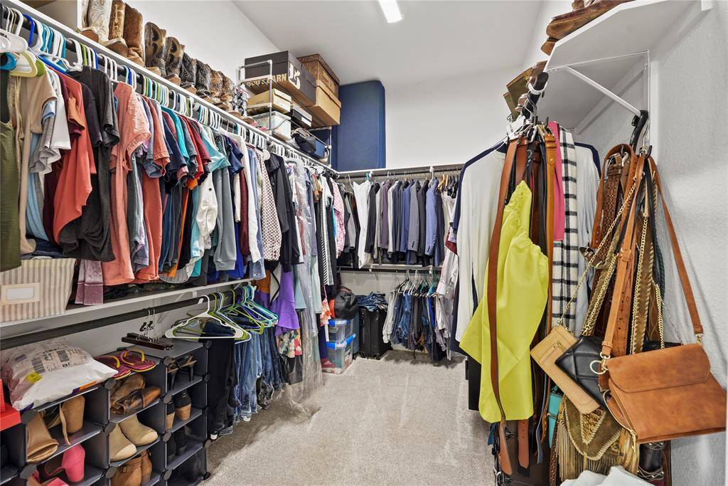 This photo shows a spacious walk-in closet with ample shelving and hanging space for clothes. It features organized sections for shoes, bags, and accessories, providing a well-structured storage solution and larger than many other floorplans in this neighborhood.