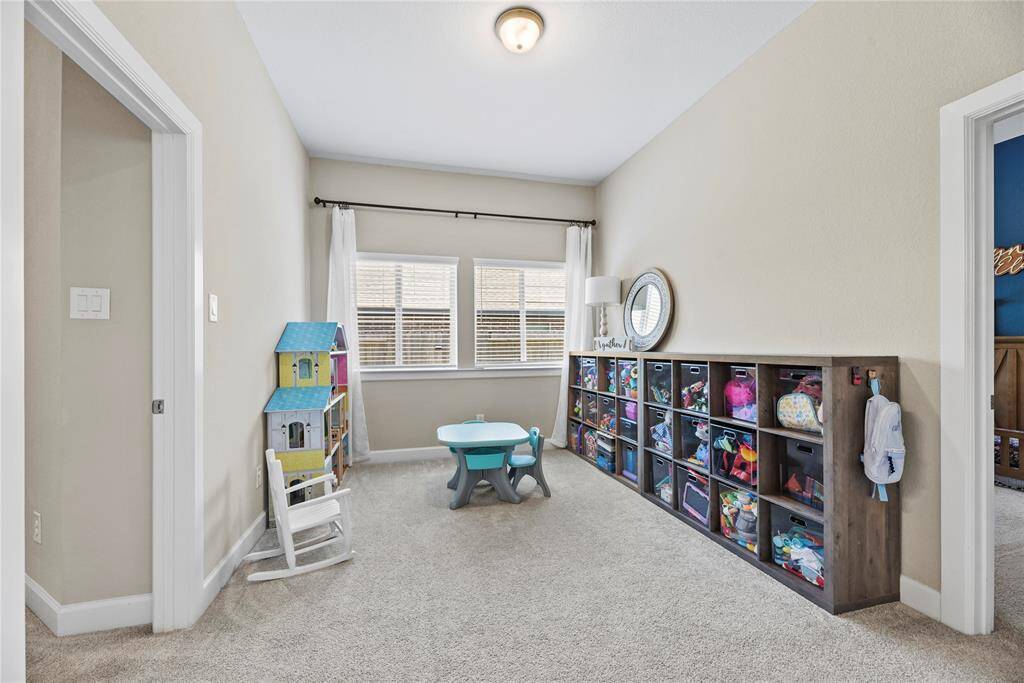 Bright playroom or flex area with carpeted flooring that is located between the two secondary bedrooms.