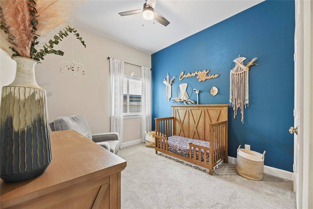 Secondary bedroom that is equipped with a fan and a beautiful accent wall.