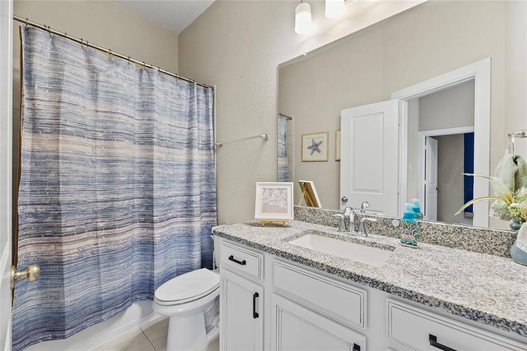 This bathroom features a granite countertop, undermount sink and white cabinetry. It includes a bathtub which is great for re sale!