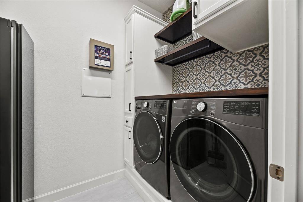 Beautiful laundry room featuring stylish patterned backsplash, and built-in shelving and cabinetry for storage. There is also ample space for a deep freezer or refrigerator to the left.