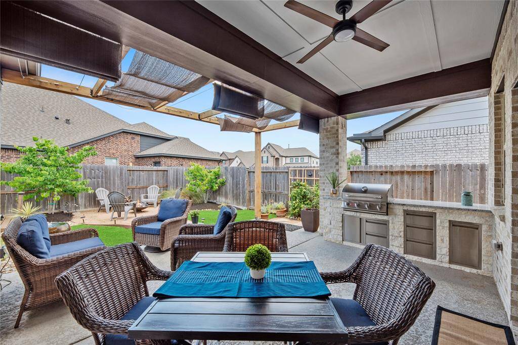 This inviting outdoor space features a covered patio with a ceiling fan, a built-in grill, large covered patio and seating area with crushed gravel pathway to a fire pit area. Perfect for entertaining and relaxing!
