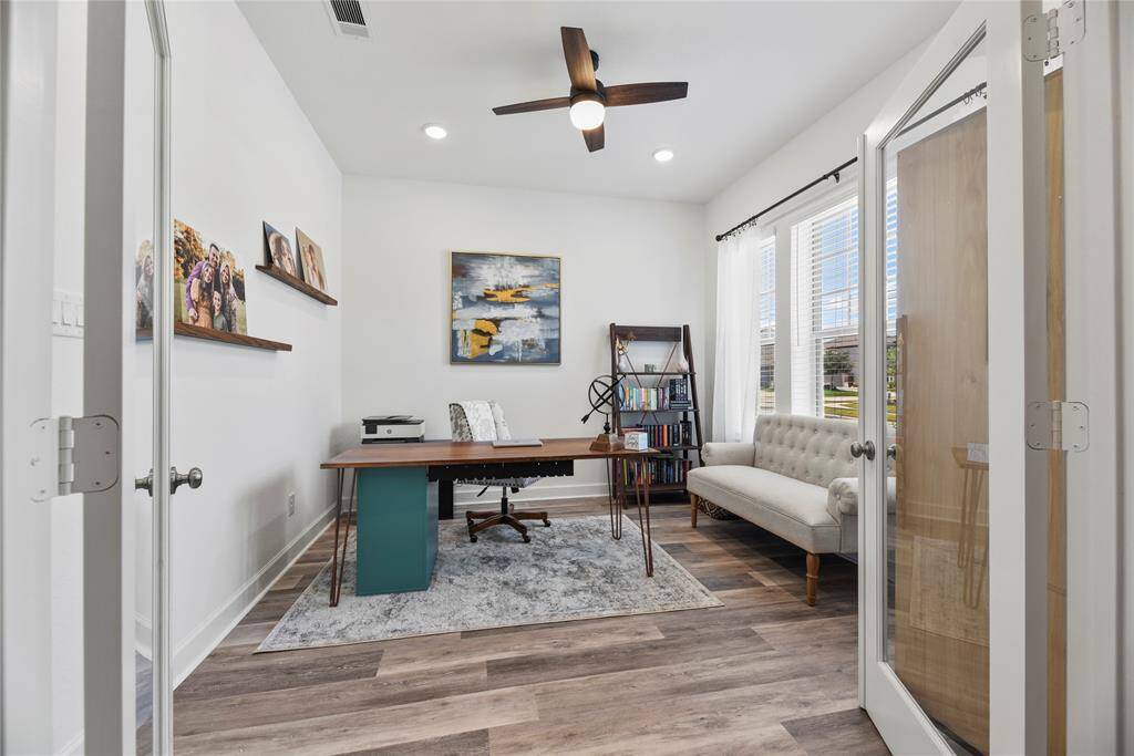 This is a bright, inviting home office with a ceiling fan and plenty of natural light. The space has a modern, clean aesthetic, perfect for productivity.
