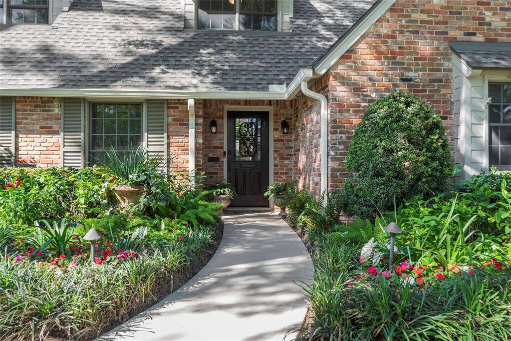 A welcoming view of the beautifully landscaped front walkway inviting you in along the framed blooming garden beds and trimmed hedges.