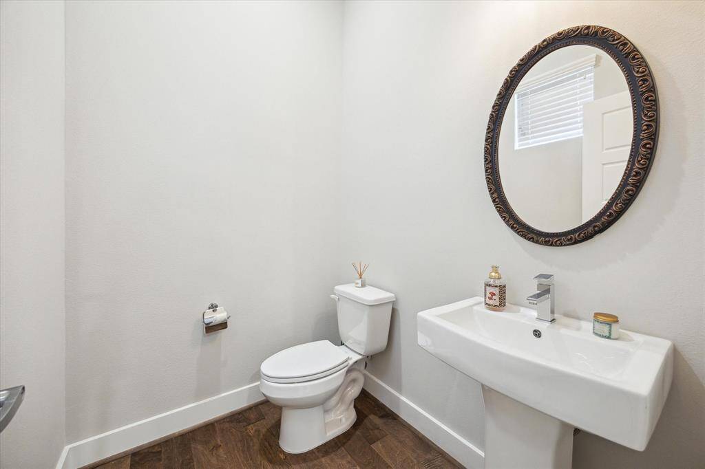 The half-bathroom has a sleek white pedestal sink. It is on the second floor, tucked away at the top of the stairs.