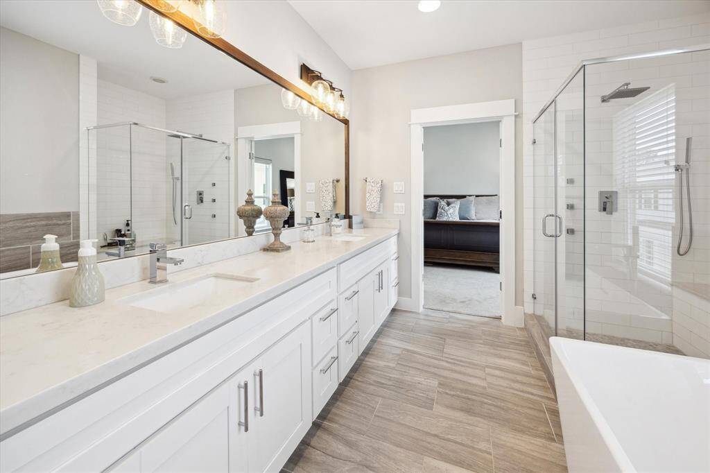 The primary bathroom features a double vanity with a large glass-enclosed shower, and a separate bathtub. Tons of storage!