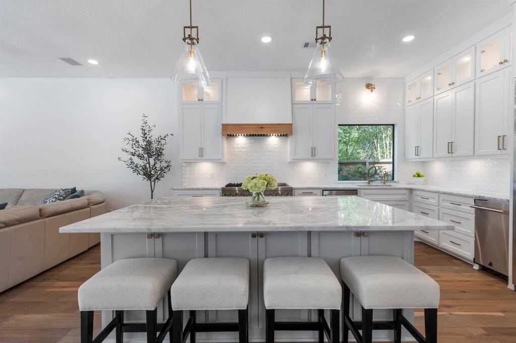 The Kraus deep stainless-steel sink with champagne bronze fixtures sits beneath a seamless picture window, flooding the room with natural light and offering peaceful outdoor views.