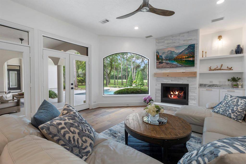 A rustic knotty alder wood mantel and custom built-ins with quartzite counters complete the space, ideal for entertaining. The family room is anchored by a stunning, seamless curved window that floods the family room with natural light and offers an unobstructed view of the backyard oasis and sparkling pool.