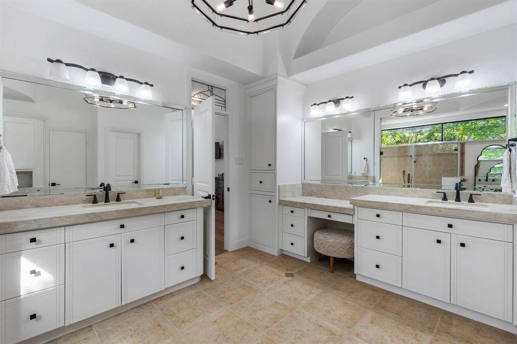 The spa like ensuite bath features luxurious Taj Mahal tumbled quartzite, dual vanities with crisp white cabinetry, and oil-rubbed bronze hardware and fixtures.