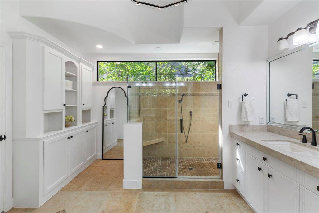 A dedicated dressing area with additional cabinetry adds convenience, and just beyond, a large step-up walk-in closet boasts extensive storage and custom built-ins.