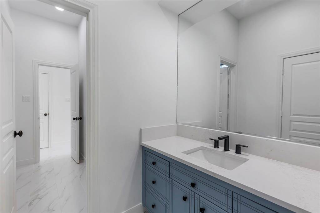 Secondary bedroom #2 offers its own vanity area with cool blue cabinetry, quartz counters and rubbed bronze hardware and fixtures.