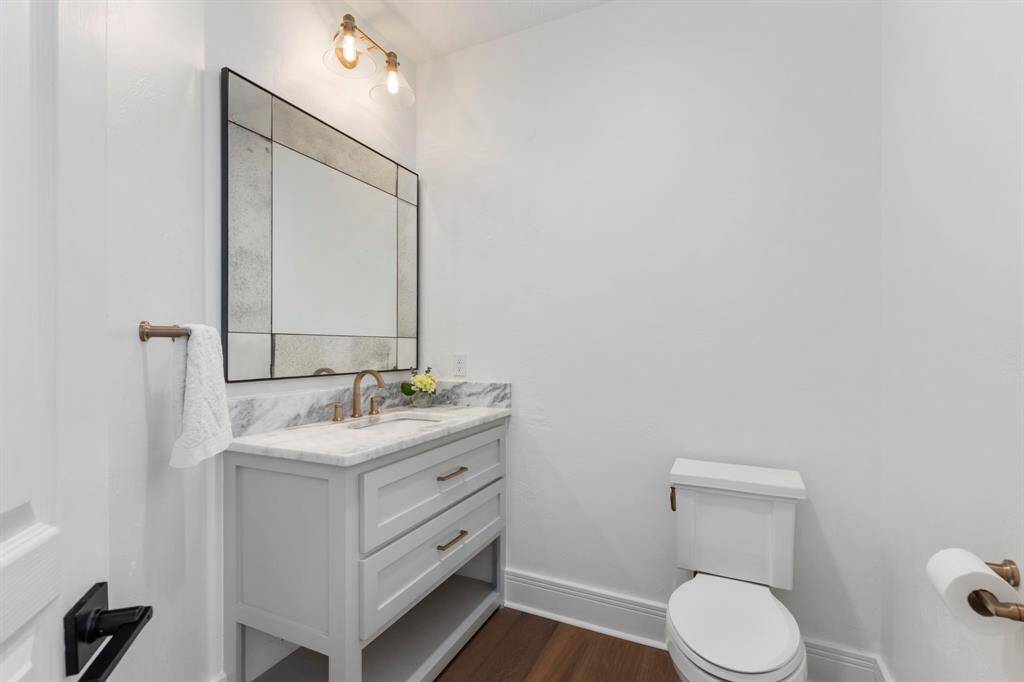 The remodeled powder bath is equally refined, showcasing a furniture-style vanity with quartzite counters, a decorative mirror, and statement lighting.