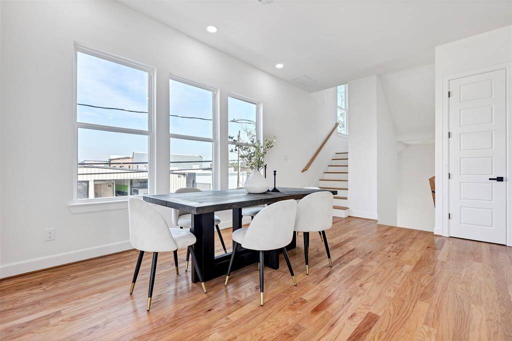 This dining area is bathed in natural light from large windows, with a staircase in the corner leading up to the third floor. (Model unit at 1234 E 23rd St. Design and finishes may vary)