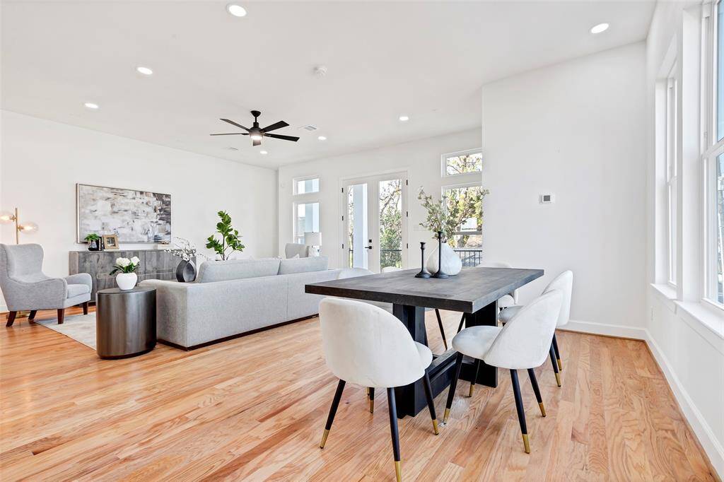An open and inviting space, this view captures both the dining and living rooms, each featuring beautiful wood floors for a warm, cohesive feel. (Model unit at 1234 E 23rd St. Design and finishes may vary)