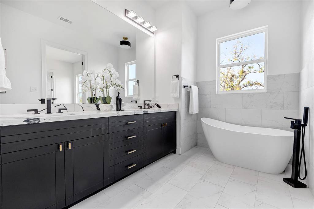 Step into this elegant primary bath, featuring a clean, timeless design with pristine white walls and flooring for a serene and sophisticated retreat. (Model unit at 1234 E 23rd St. Design and finishes may vary)